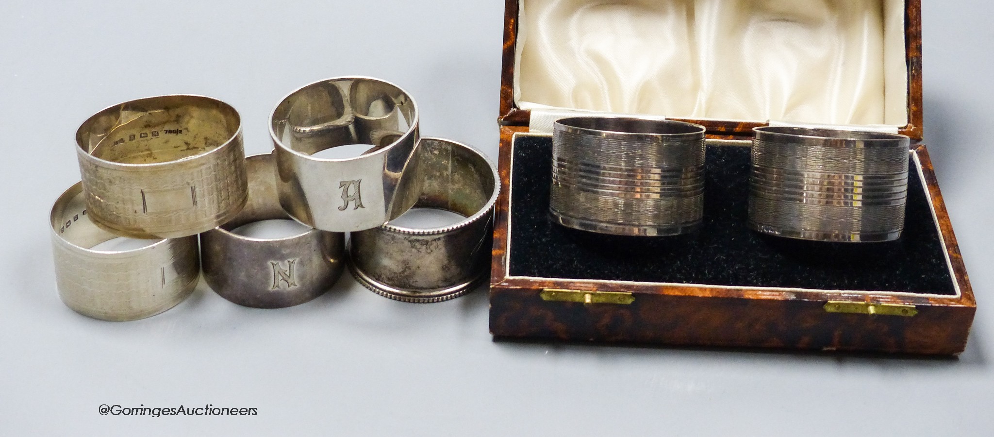 A cased pair of George V silver napkin rings, one other pair of silver napkin rings and three other silver napkin rings, 7oz.